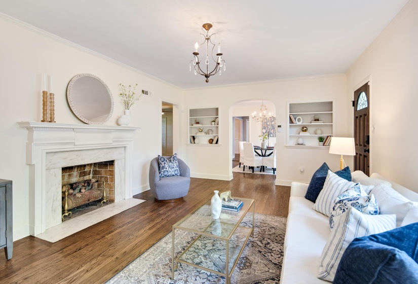 Living area with wood finished floors, a chandelier, arched walkways, built in features, and visible vents