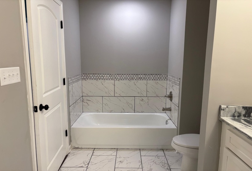 Bathroom featuring vanity, marble look tile flooring, and a garden tub