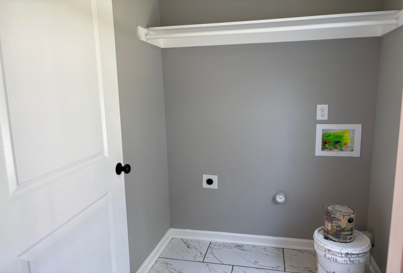 Laundry area with electric dryer hookup, hookup for a washing machine, and light marble finish floors