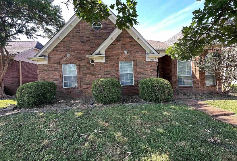 Traditional home with a front lawn, brick siding, and a shingled roof