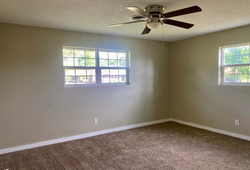 Carpeted empty room with ceiling fan and a textured ceiling