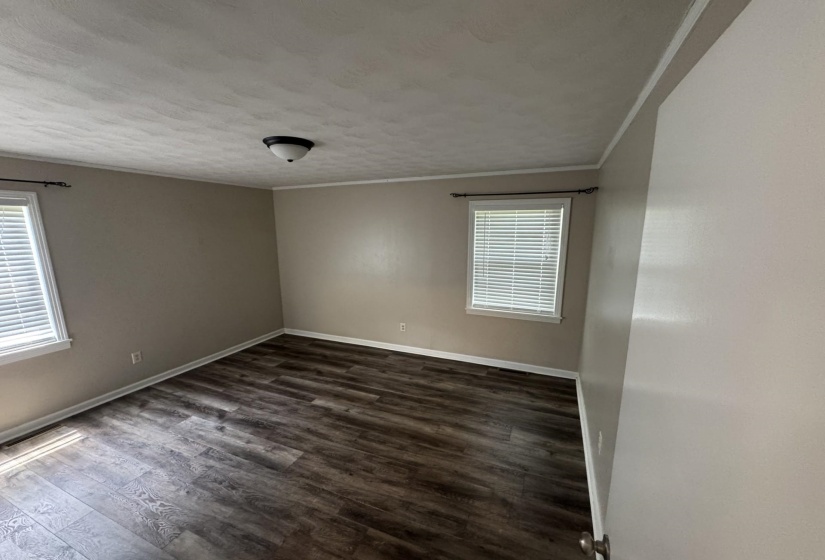 Spare room with dark wood-type flooring, ornamental molding, and a textured ceiling