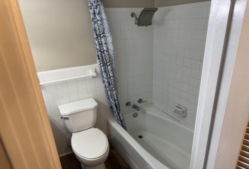 Bathroom with shower / bath combo with shower curtain, tile walls, and wainscoting