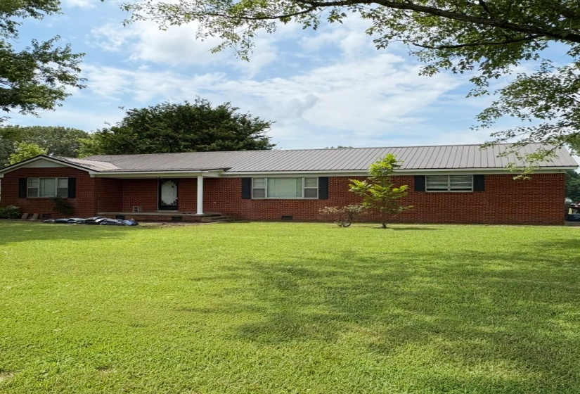 Ranch-style home with a front lawn, a metal roof, and brick