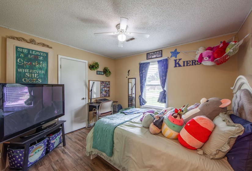 Bedroom featuring wood finished floors, a textured ceiling, crown molding, and a ceiling fan
