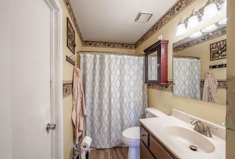 Full bathroom with a textured ceiling, vanity, wood finished floors, and a shower with shower curtain