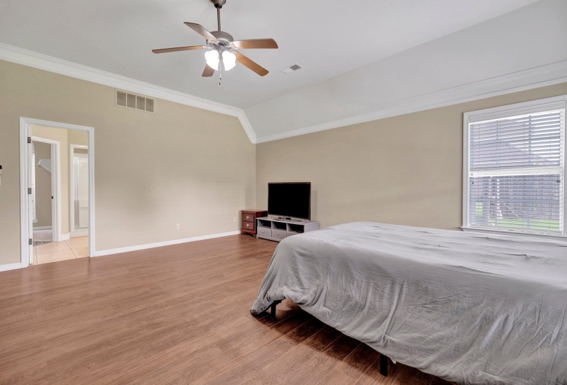 Bedroom with crown molding, light wood-style floors, vaulted ceiling, and a ceiling fan