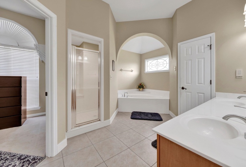 Full bath featuring a bath, a stall shower, tile patterned flooring, and double vanity