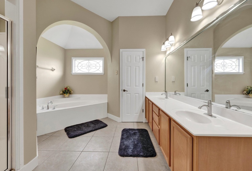Full bathroom featuring a garden tub, double vanity, healthy amount of natural light, and tile patterned floors