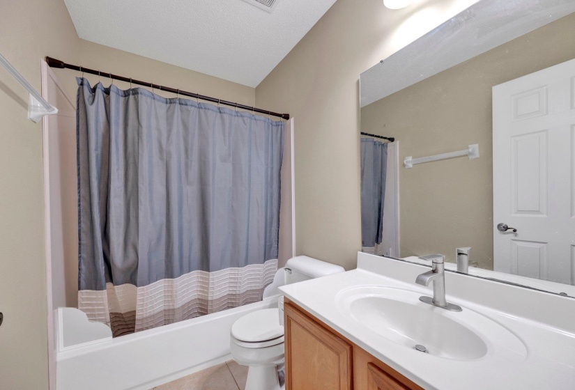 Full bath featuring vanity, shower / bathtub combination with curtain, and tile patterned flooring