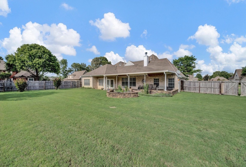 Rear view of house featuring a chimney, a fenced backyard, brick siding, and a patio area