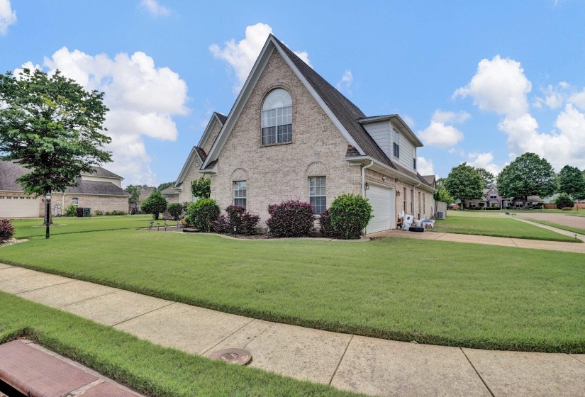 View of side of home with brick siding, a garage, a yard, and concrete driveway