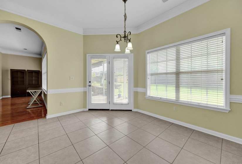 Unfurnished dining area featuring arched walkways, ornamental molding, light tile patterned flooring, and a chandelier