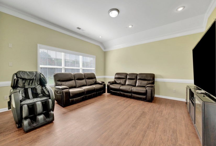 Living room with ornamental molding, wood finished floors, and recessed lighting