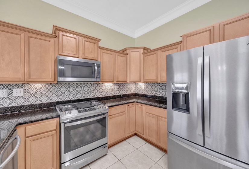 Kitchen featuring appliances with stainless steel finishes, light brown cabinetry, crown molding, and light tile patterned floors