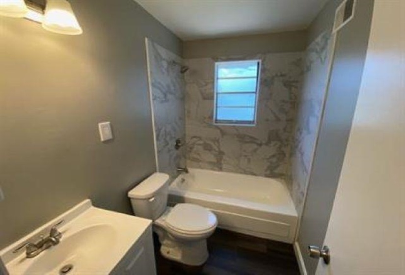 Bathroom featuring vanity, bathing tub / shower combination, and wood finished floors