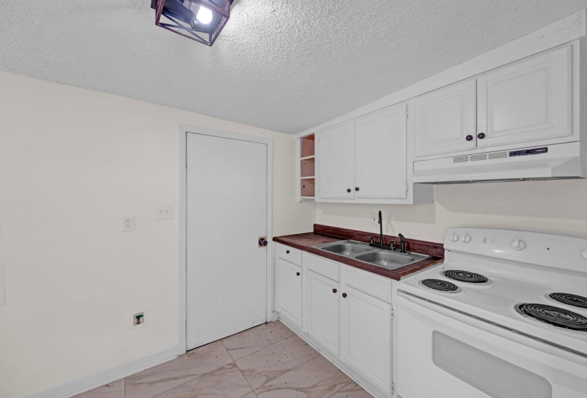 Kitchen with electric stove, under cabinet range hood, open shelves, a textured ceiling, and white cabinets