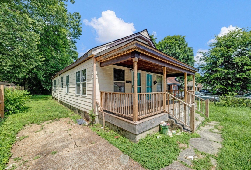 Shotgun-style home featuring covered porch and a front lawn