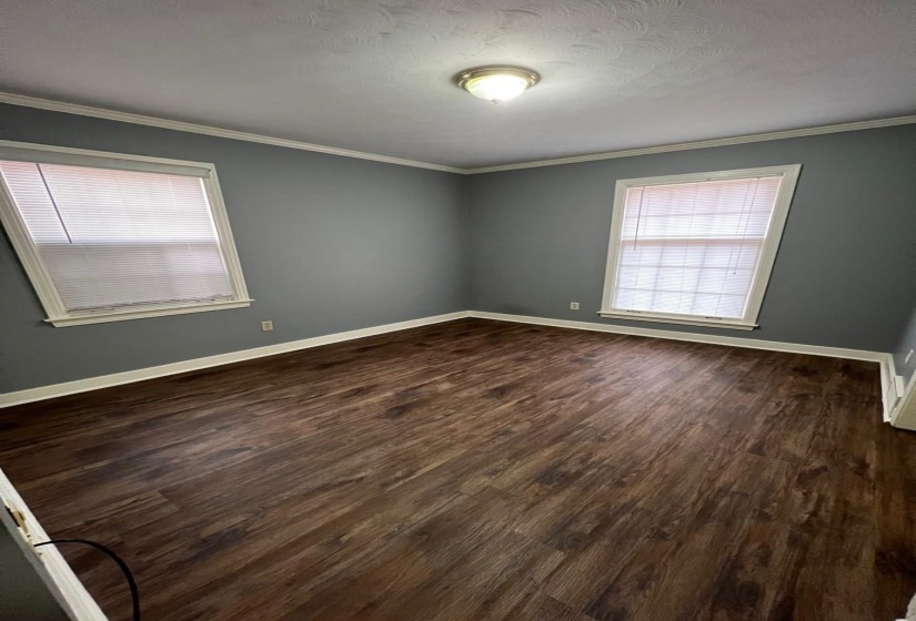 Unfurnished room with healthy amount of natural light, dark wood finished floors, and ornamental molding