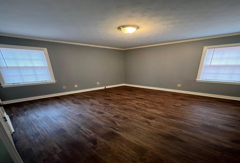 Empty room with dark wood-style floors and crown molding