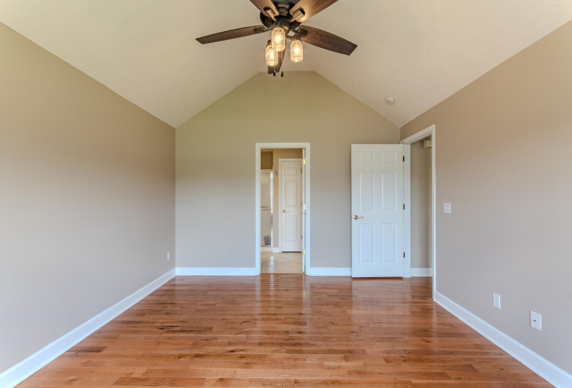 Unfurnished bedroom featuring lofted ceiling, light wood-type flooring, and a ceiling fan