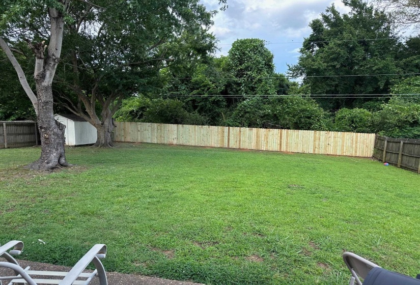 Fenced backyard featuring a storage shed
