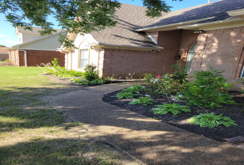 View of property exterior featuring brick siding, roof with shingles, and a yard