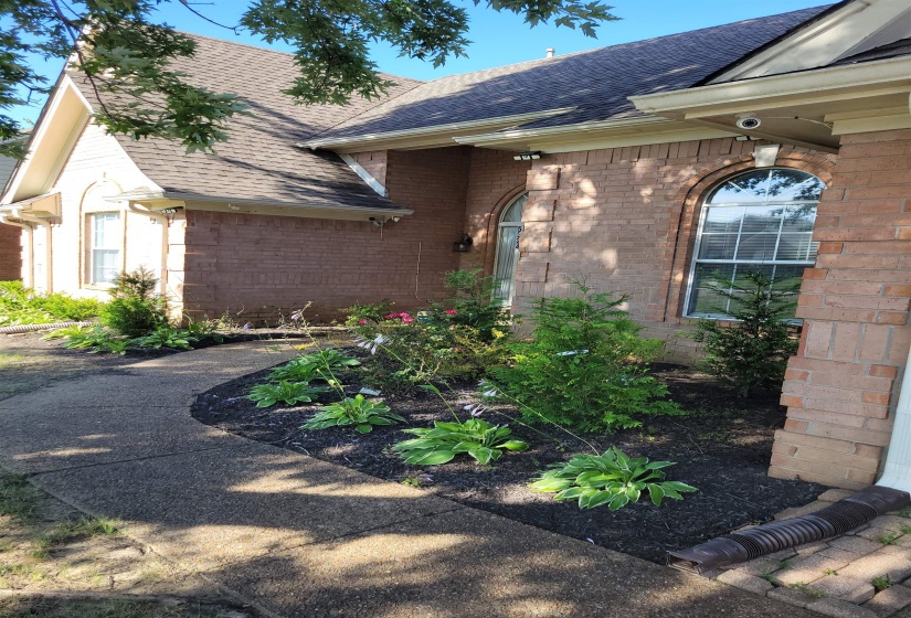 View of home's exterior featuring a shingled roof, brick siding, and a surveillance system