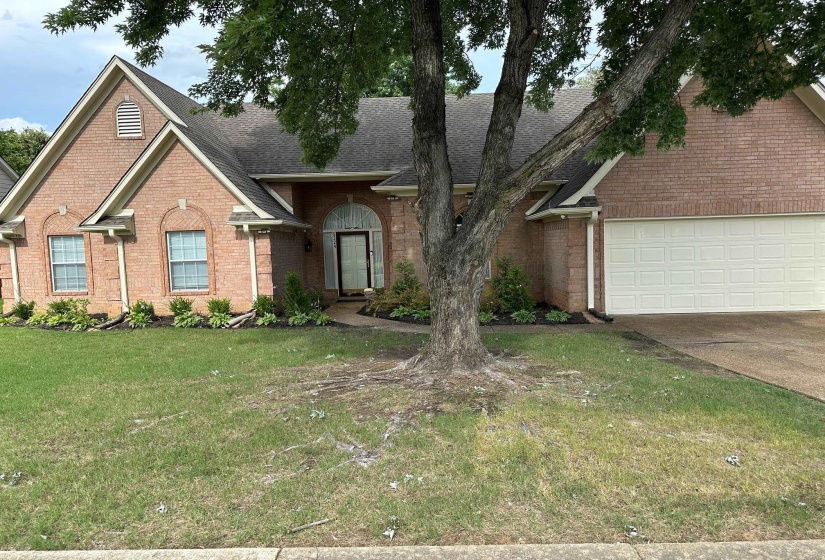 View of front of house featuring brick siding, concrete driveway, roof with shingles, a front lawn, and a garage