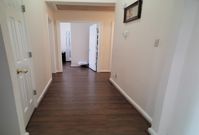 Hallway with dark wood-type flooring and baseboards