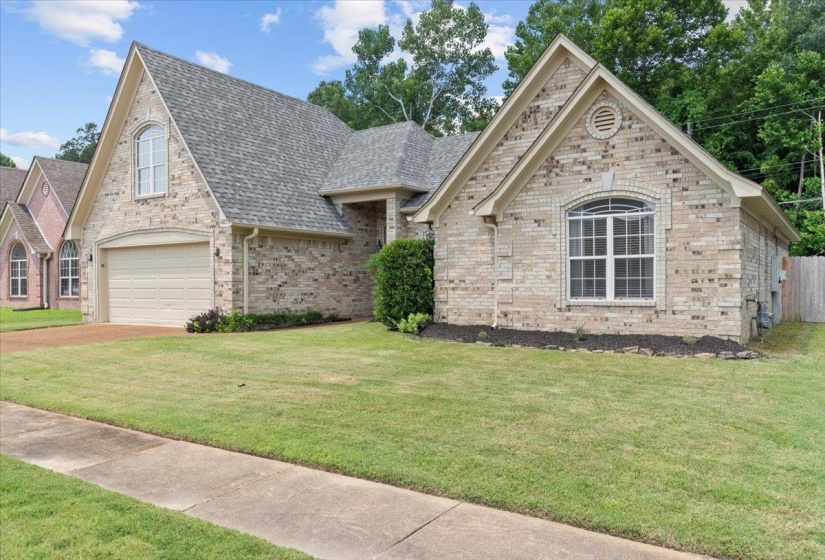 View of front of property featuring roof with shingles, driveway, a front lawn, and a garage