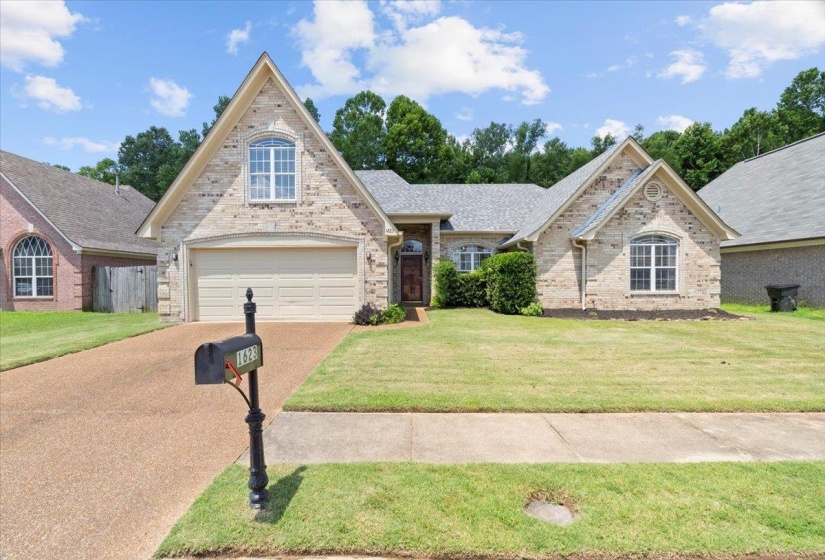 Traditional-style home with concrete driveway, a garage, a front yard, and brick siding
