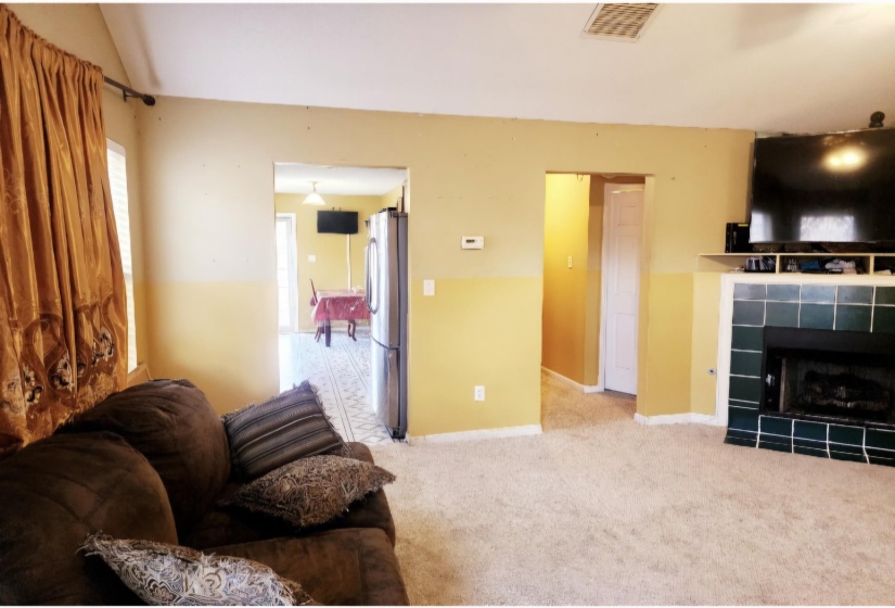 Living room featuring light colored carpet, a fireplace, and vaulted ceiling