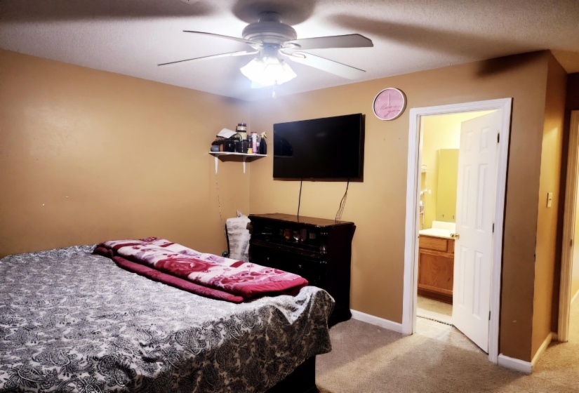 Bedroom featuring connected bathroom, ceiling fan, and light colored carpet