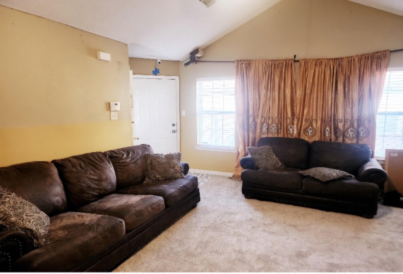 Carpeted living room featuring lofted ceiling