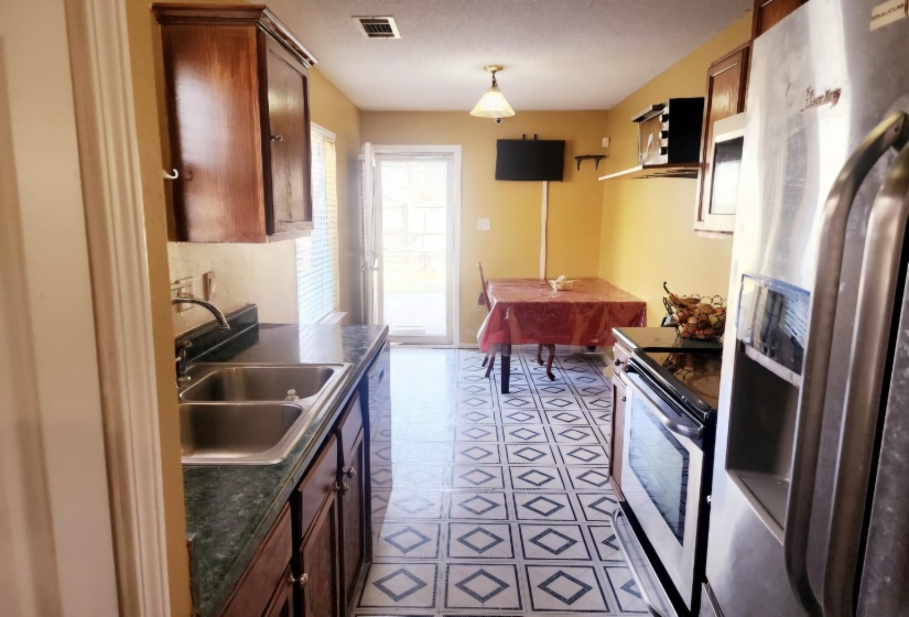 Kitchen featuring stainless steel refrigerator with ice dispenser, stove, and sink