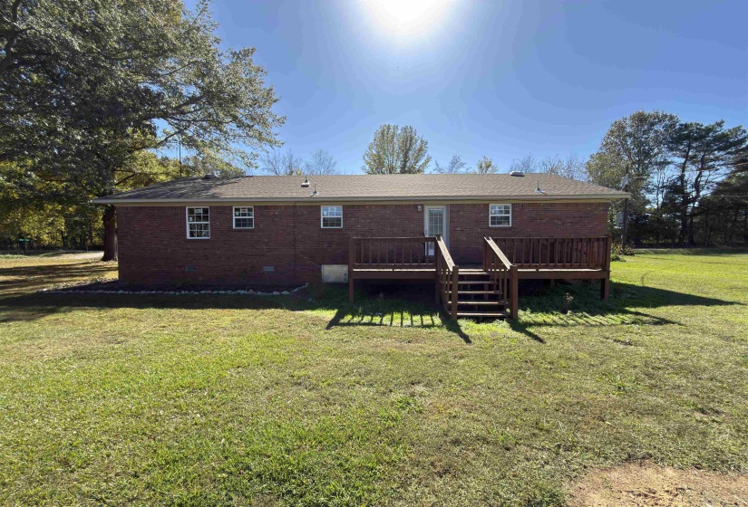 Rear view of house featuring a deck, a lawn, brick siding, and crawl space