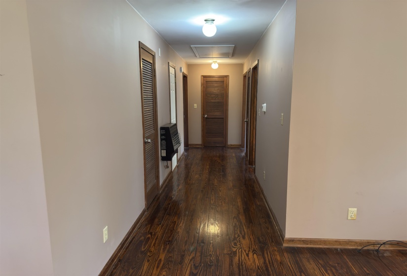 Hallway with dark wood-type flooring and heating unit