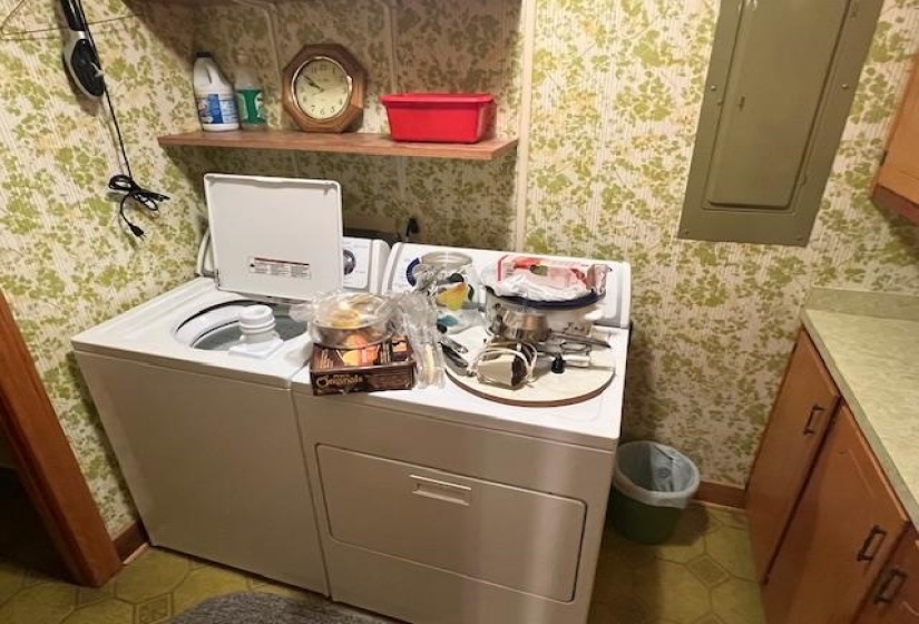 Laundry area featuring light tile patterned flooring, electric panel, and washing machine and clothes dryer
