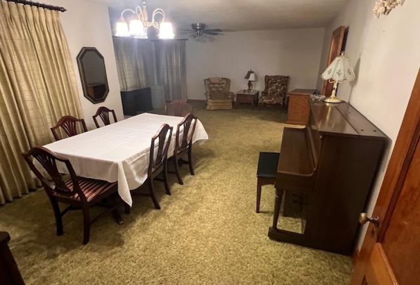 Carpeted dining area featuring ceiling fan with notable chandelier