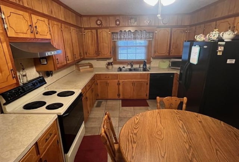 Kitchen with sink, black appliances, and range hood