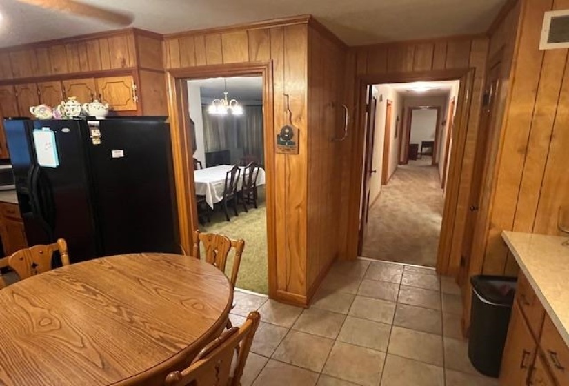 Kitchen featuring pendant lighting, wood walls, light carpet, black fridge, and a chandelier