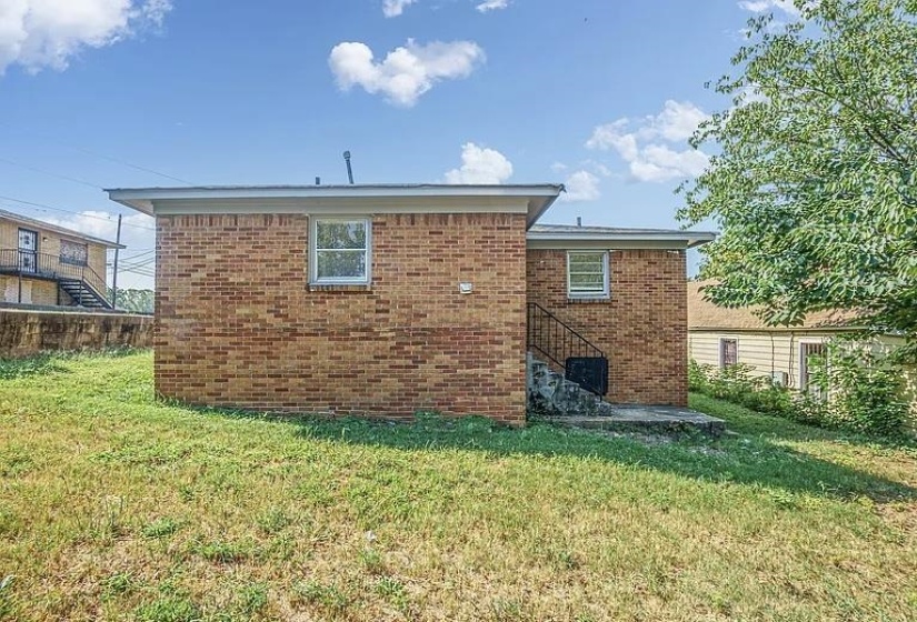 Rear view of property with brick siding and stairs