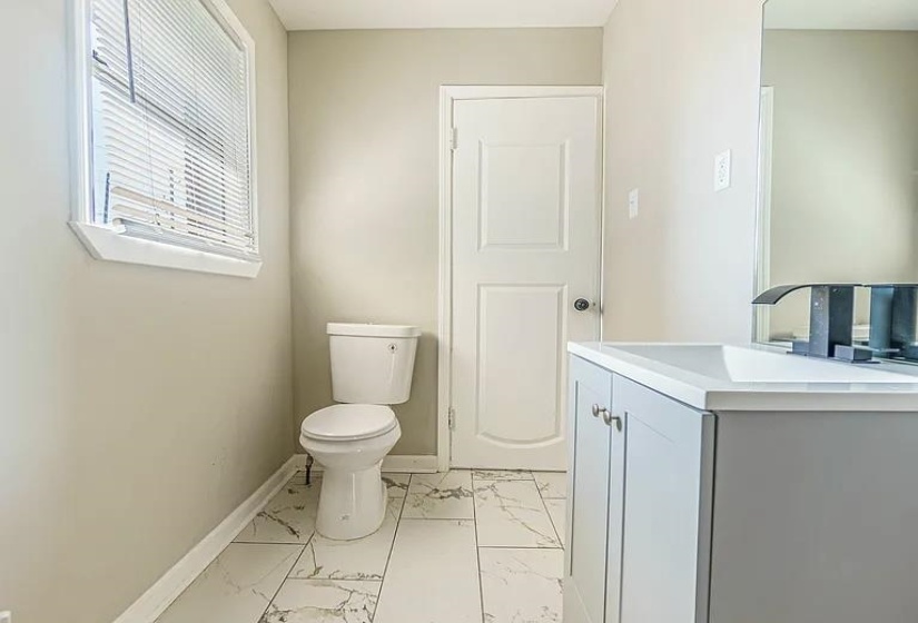 Half bathroom with marble look tiles and vanity