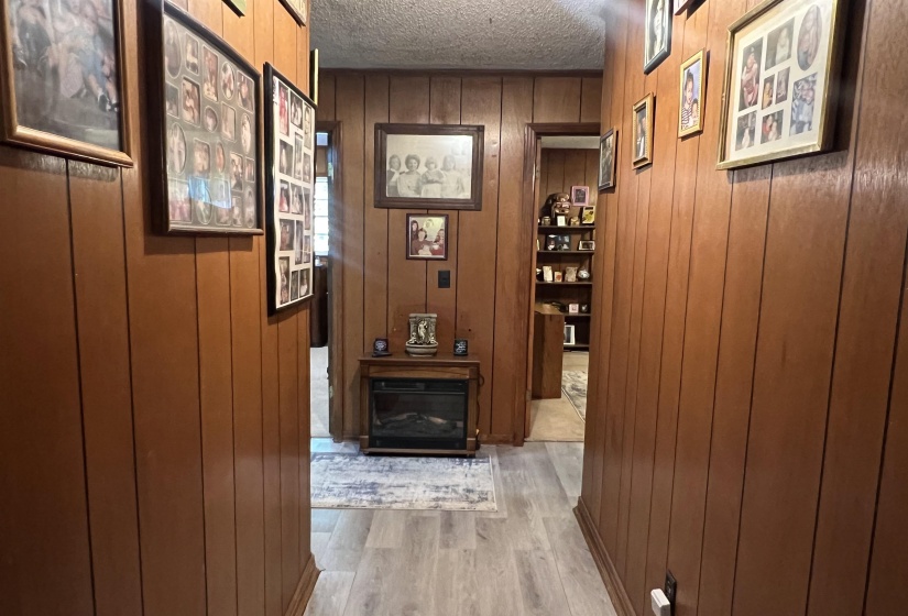Hall with a textured ceiling, hardwood / wood-style flooring, and wooden walls