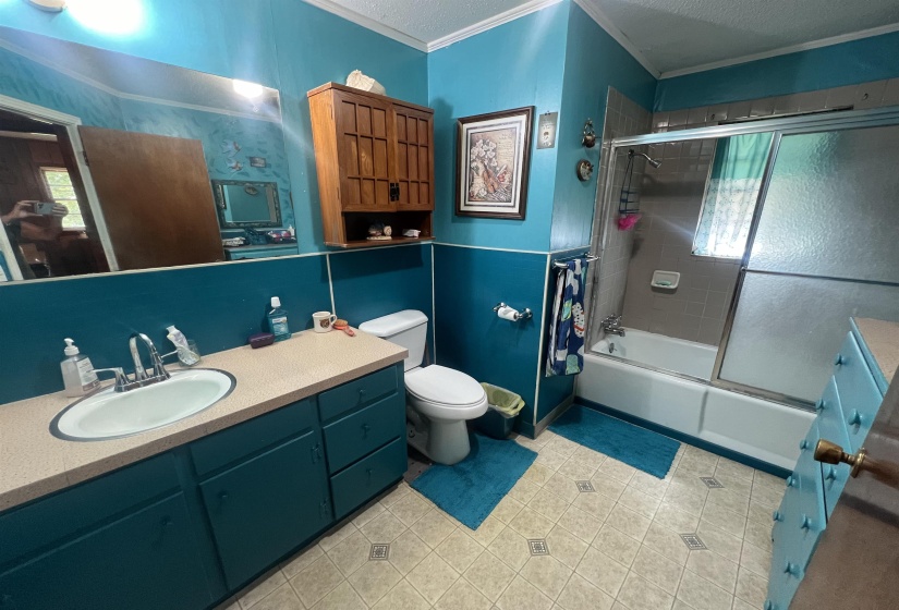 Full bathroom with tile patterned floors, vanity, bath / shower combo with glass door, and toilet