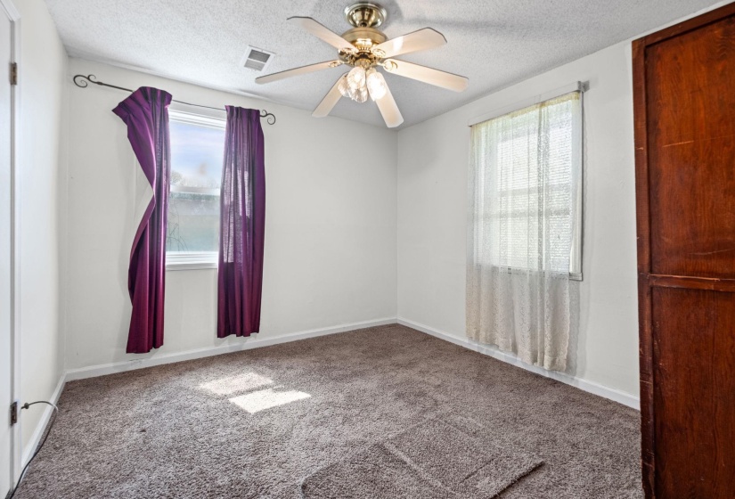 Carpeted empty room featuring a ceiling fan, a textured ceiling, and healthy amount of natural light