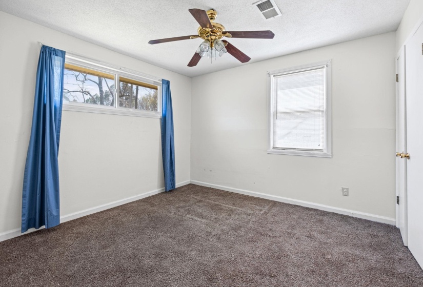 Empty room featuring dark colored carpet, a ceiling fan, and a textured ceiling
