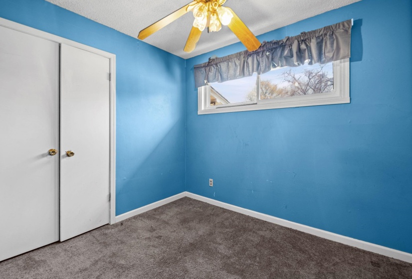 Unfurnished bedroom featuring dark carpet, a closet, ceiling fan, and a textured ceiling
