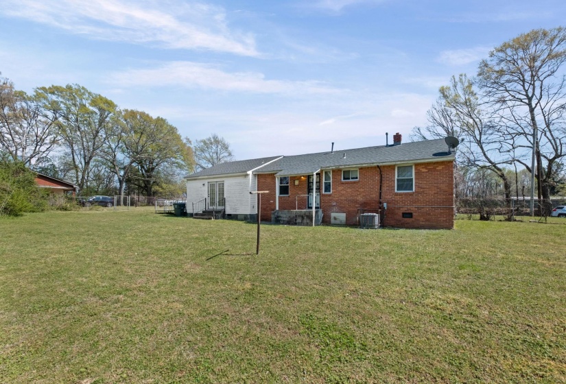 Back of property featuring crawl space, a lawn, brick siding, and a chimney